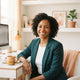 A friendly and professional headshot of a diverse woman smiling in a bright, modern office space.